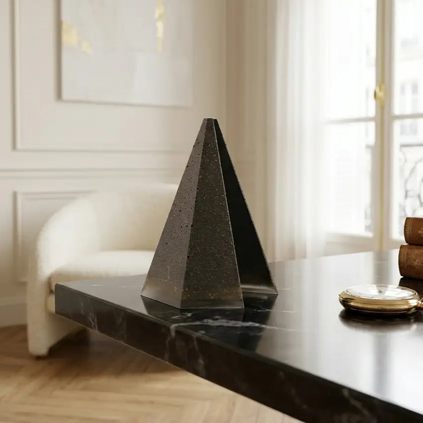 Gedenkhommage mit der Trauerpyramide PRISME, integriert in die Dekoration eines gemütlichen Wohnzimmers neben einer Grünpflanze