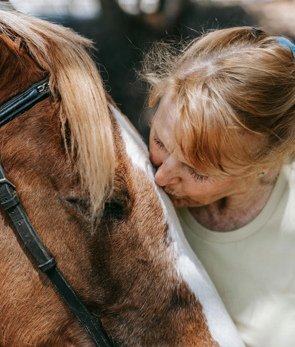 Femme senior à côté de son cheval, incarnant une vie d'amitié équestre et le respect de la mémoire de son animal de cœur